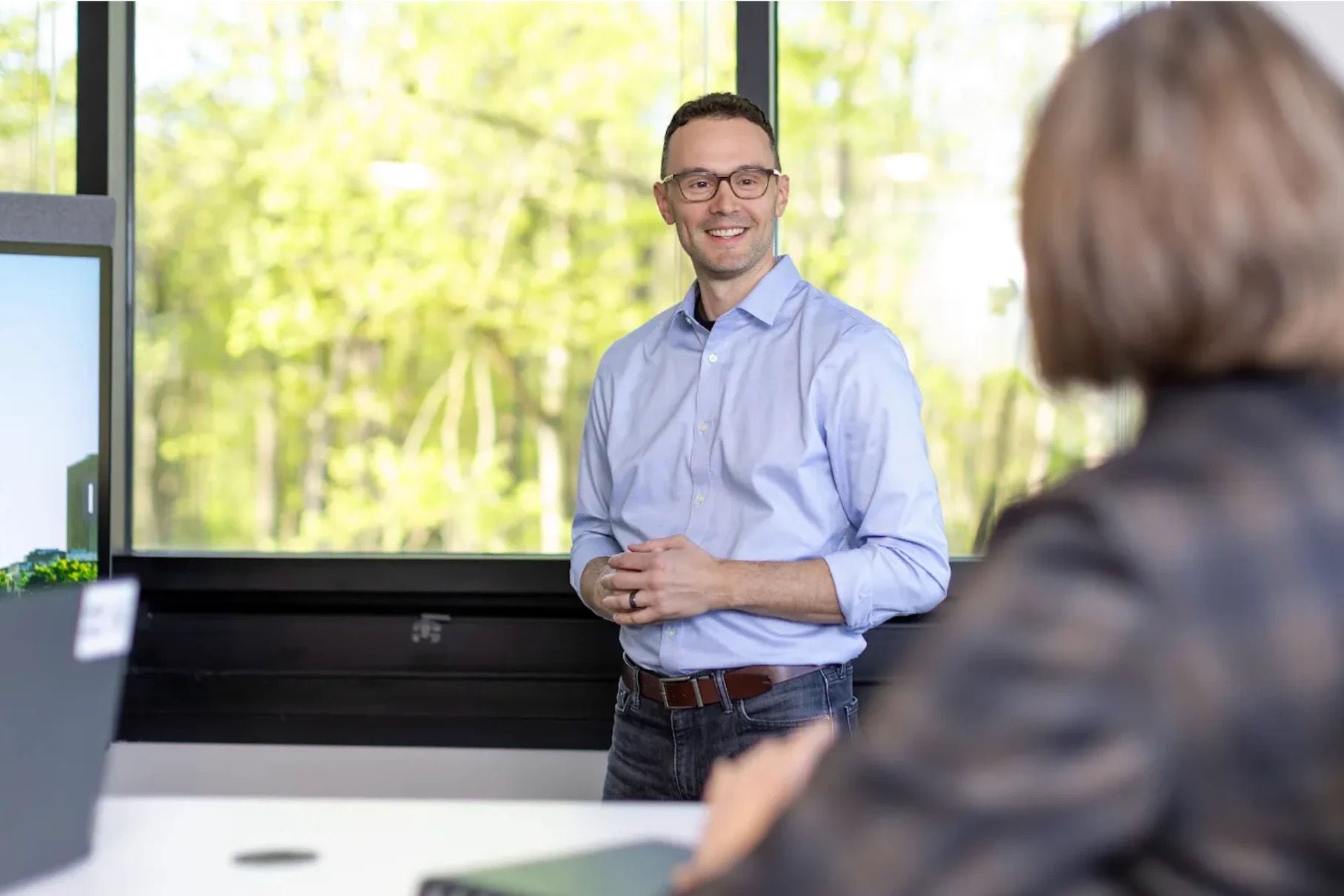 A man in a blue shirt stands in an office setting