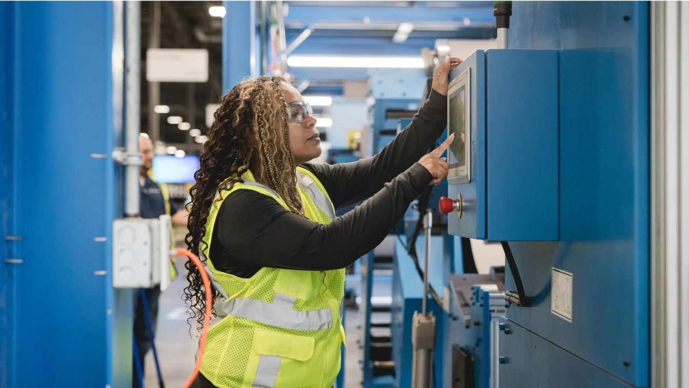 A technician making adjustments on a control panel in a mechanical room