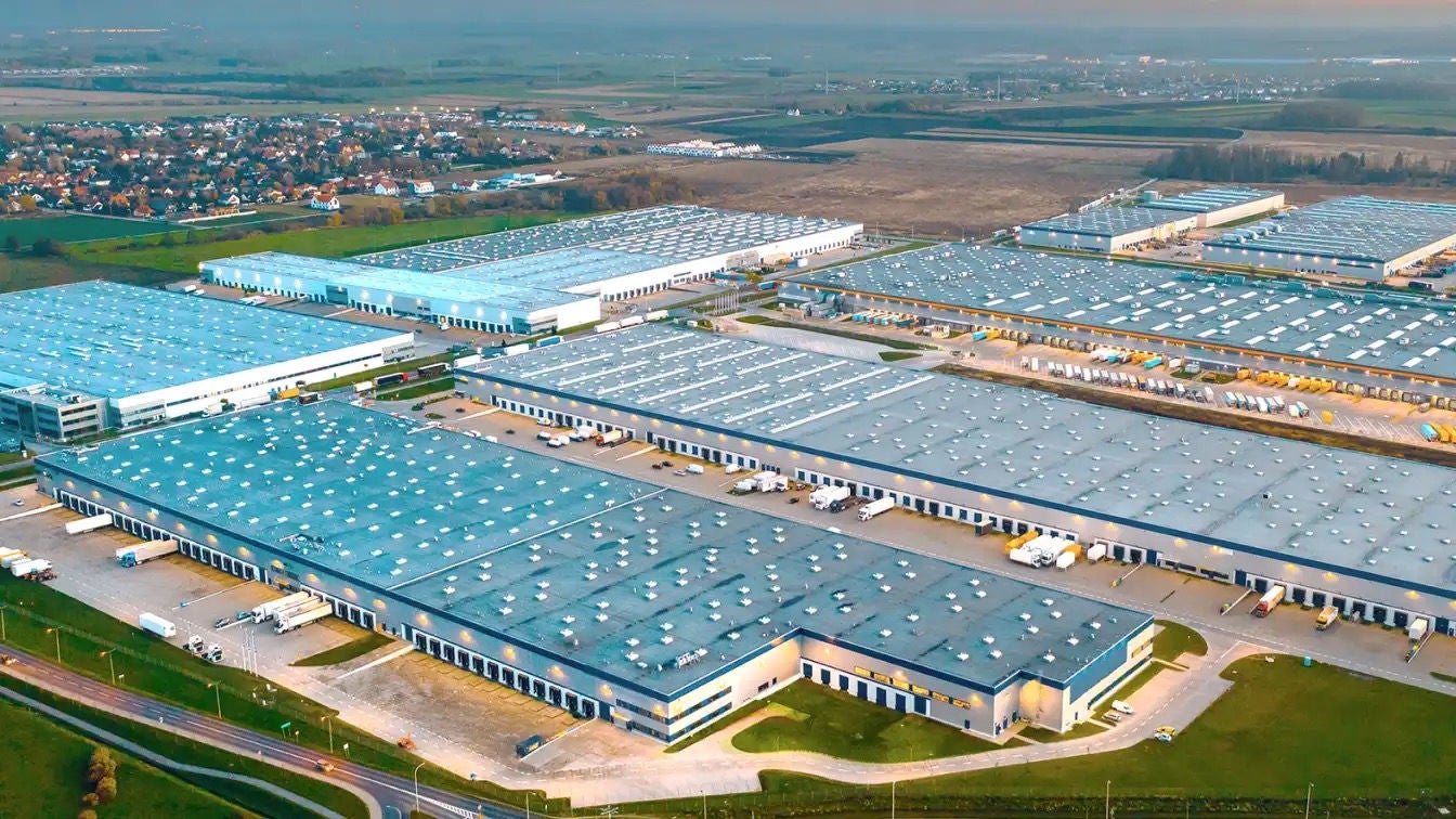 Un groupe de grands bâtiments industriels avec semi-remorques amarrés à certaines des baies de chargement