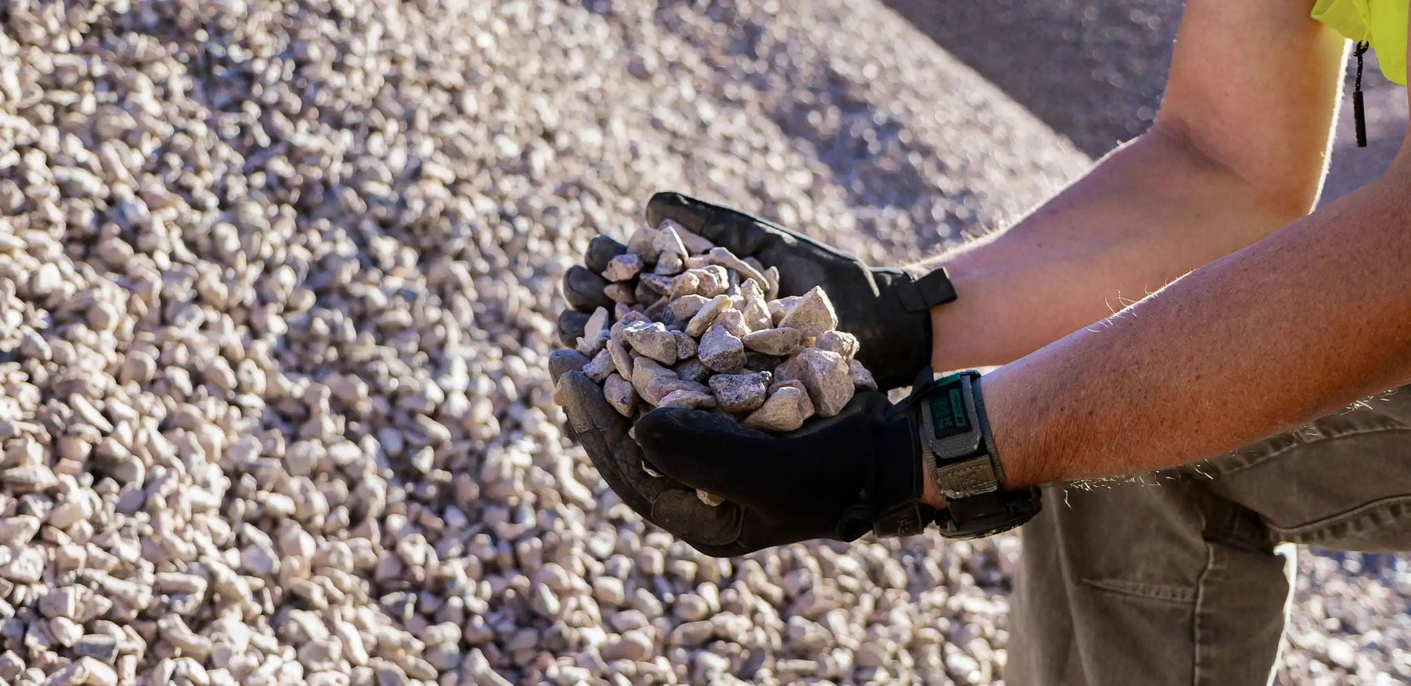 Gloved hands holding a handful of aggregate rocks