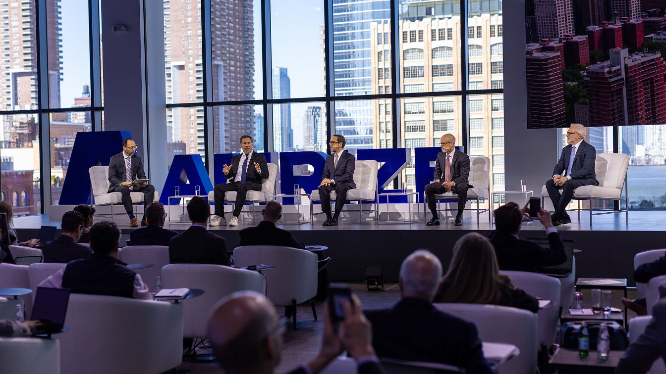 Members of the Amrize leadership team sit on a stage in front of a seated crowd.