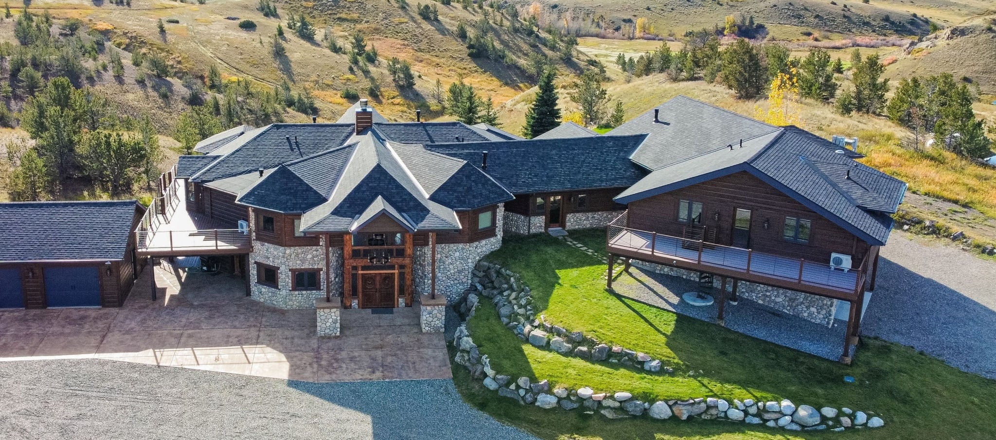 Sprawling modern home in rural setting featuring grey shingled roof