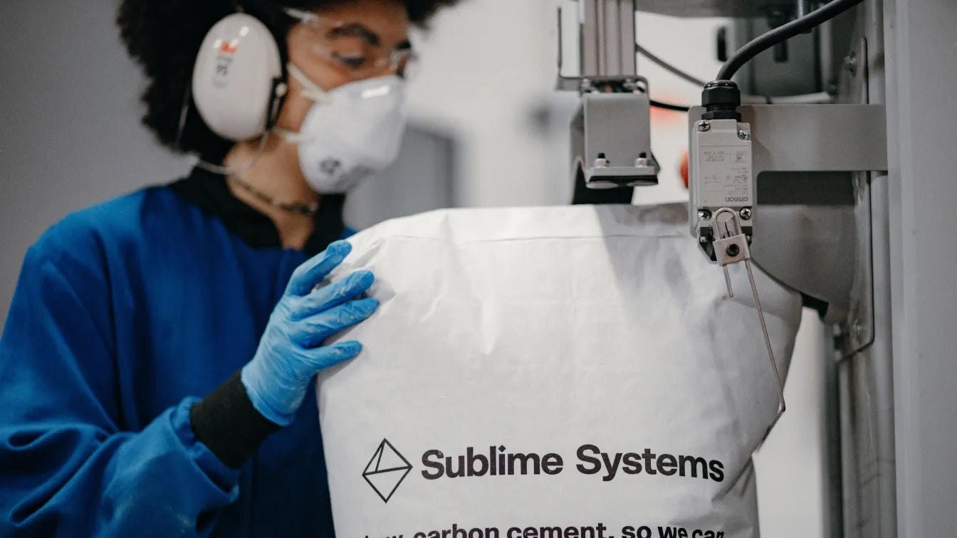 A worker holding a large bag of Sublime cement 