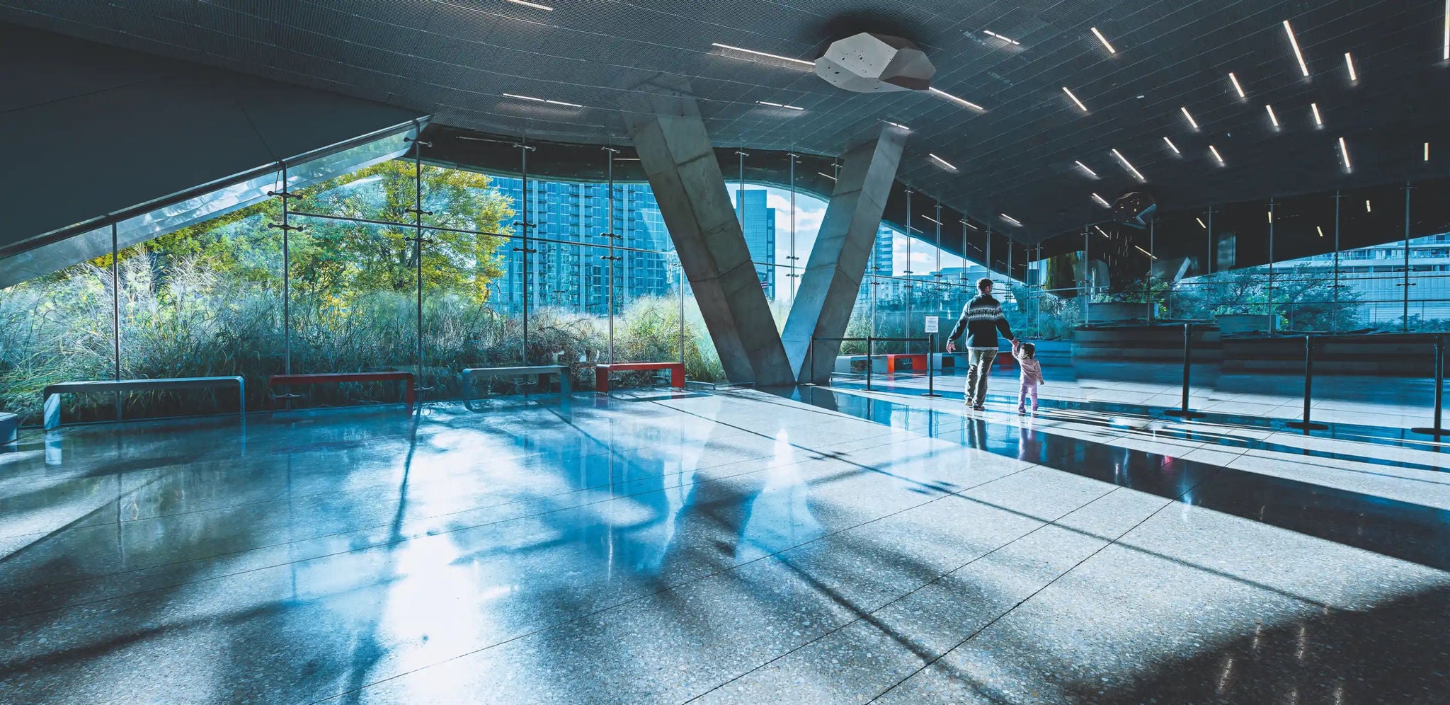 A large and impressive modern lobby with concrete support beams and an unusual slanted ceiling