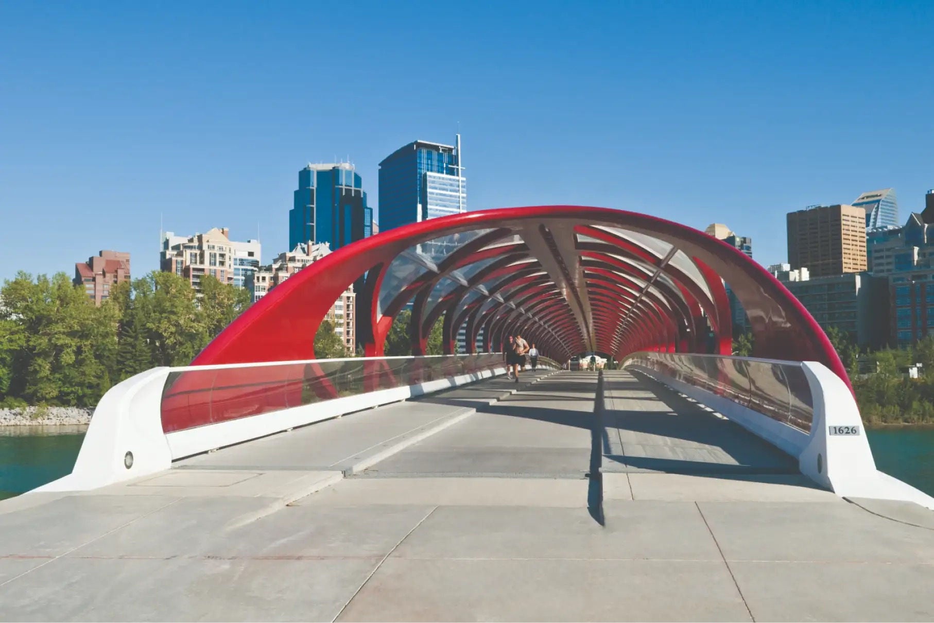 A bridge with a stylish red roof, in an urban environment with towers in the background.