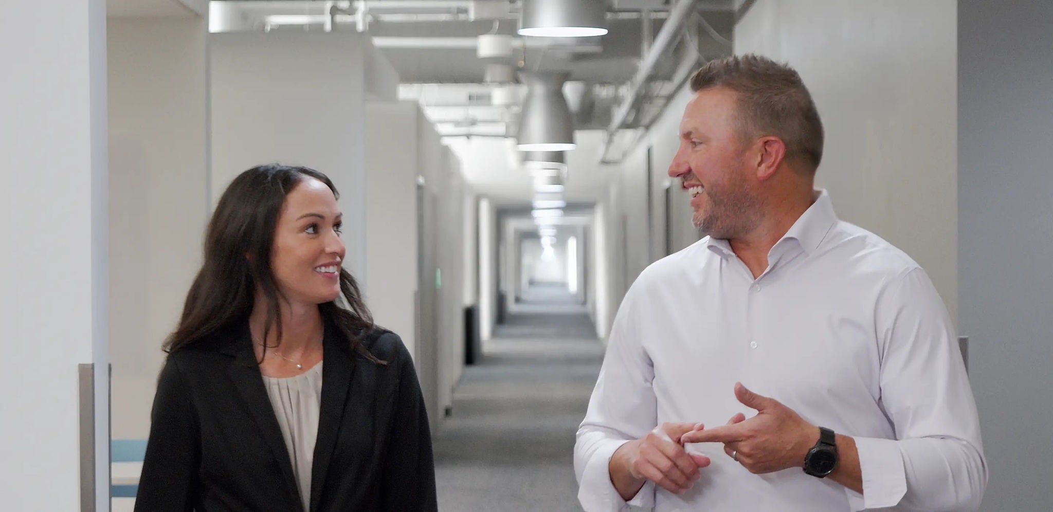  Deux collègues discutent en marchant dans un couloir de bureau