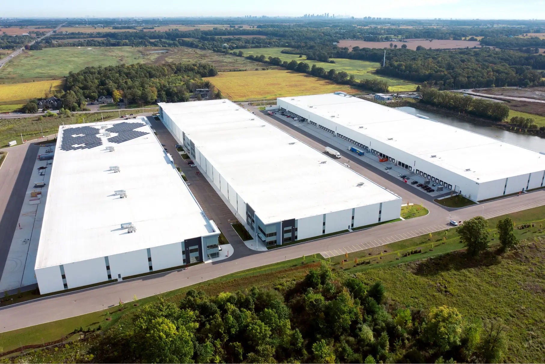 Aerial view of three sprawling white industrial buildings surrounded by greenery