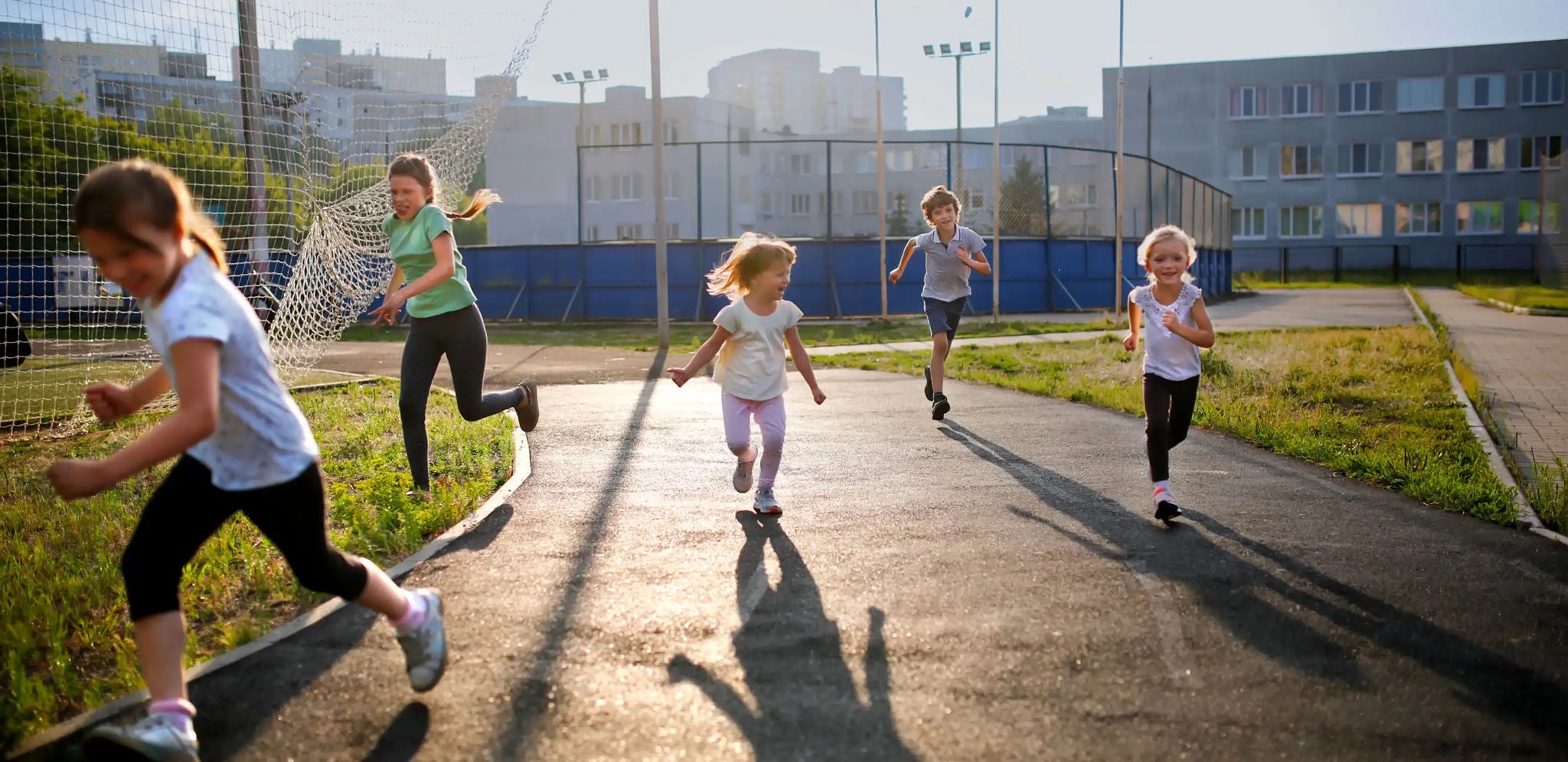 Children running along an asphalt path in a playground
